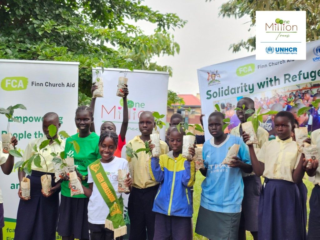 Children and partners holding seedlings with Finn Church Aid and UNHCR banners